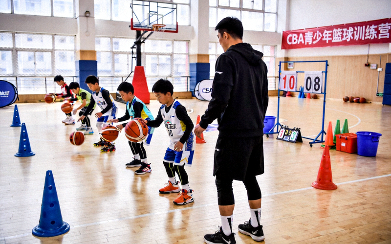 CBA青少年篮球训练营场景，孩子们在教练指导下练习